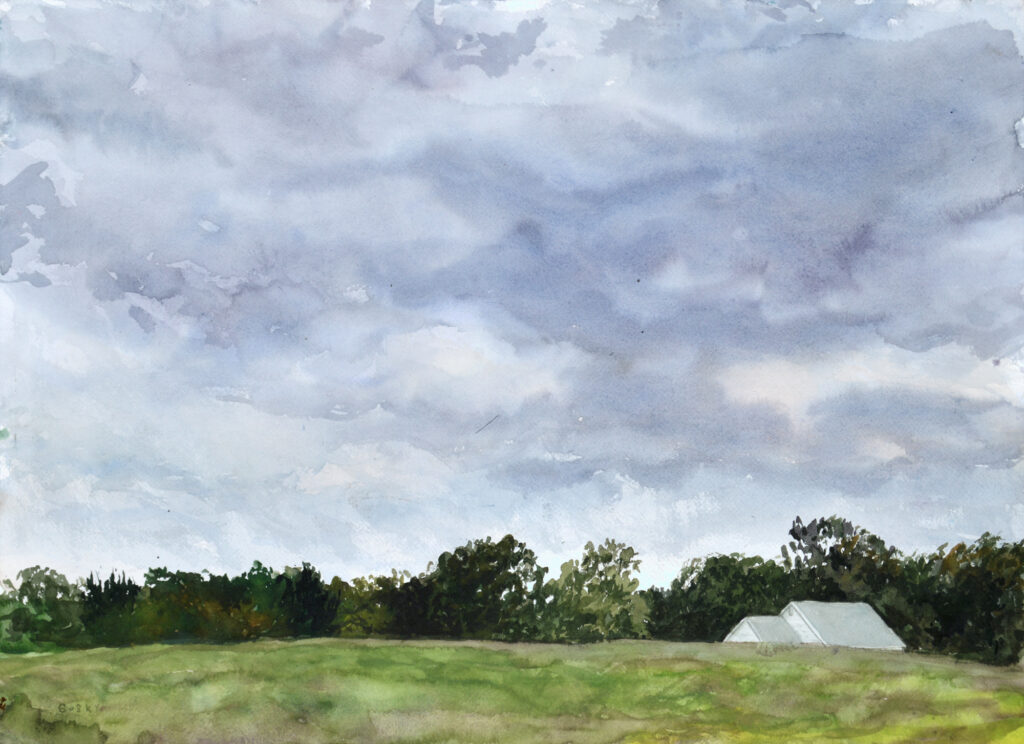 Mid-sized watercolor painting, dark lowering sky looms in violets, cobalts, grays and browns, over an open field rimmed with deciduous trees in shades of greens, with the roof of a low white house peering over the field's edge