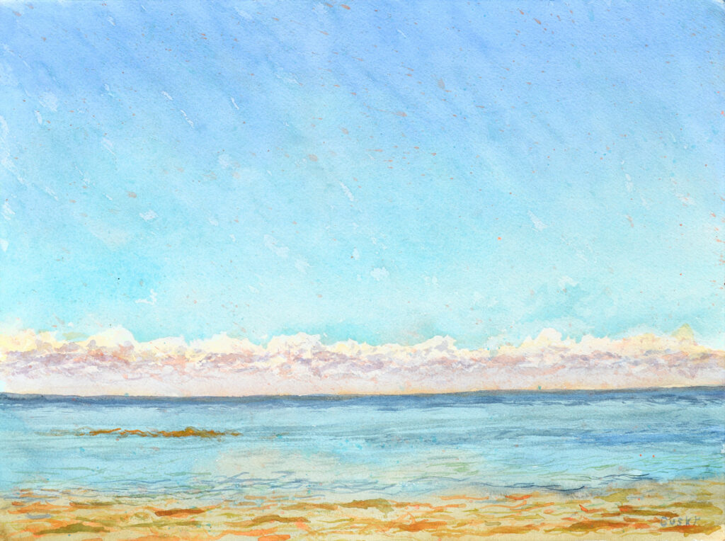 Bright mid day, clear sky over a row of shining clouds over a turqoise and orange sea